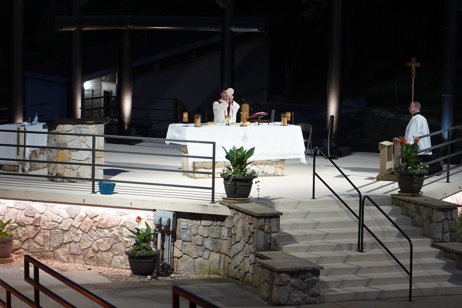 Father John Schmitz, pastor of St. Patrick Parish in Laurie and the Mission of St. Philip Benizi in Versailles, elevates the Most Blessed Sacrament during the Vigil Mass for the Solemnity of the Most Holy Body and Blood of Christ, the evening of June 18 at the outdoor altar of the National Shrine of Mary, Mother of the Church, in Laurie.